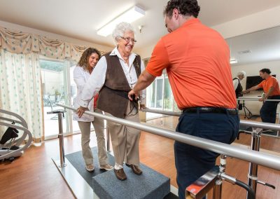two rehab therapists and a resident in the rehab gym at Monterey Care Center